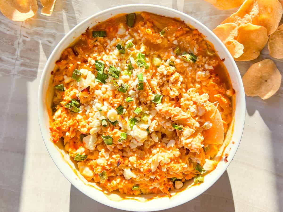 Finished cottage cheese buffalo chicken dip in a bowl with chips around it.