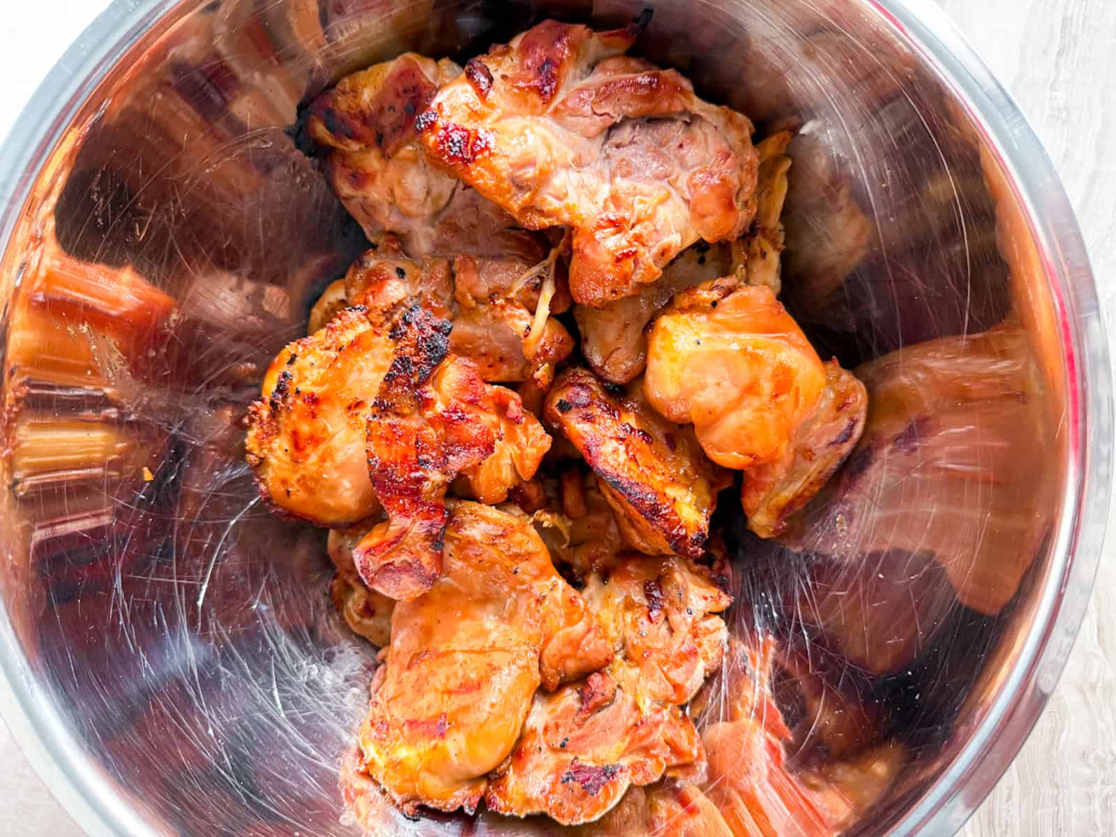 Cooked teriyaki chicken thighs in a metal bowl.