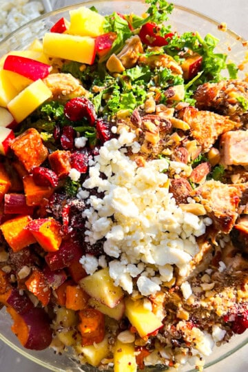 Sweetgreen harvest bowl with chicken, roasted sweet potatoes, goat cheese in a clear bowl.