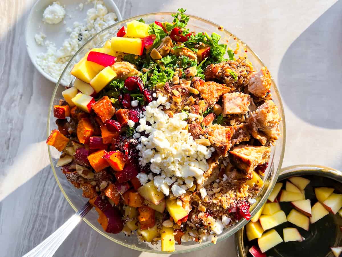 Sweetgreen harvest bowl with chicken, roasted sweet potatoes, goat cheese in a clear bowl.