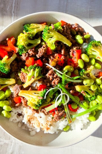 Teriyaki beef bowls filled with ground beef, edamame, rice, red bell pepper, and broccoli.