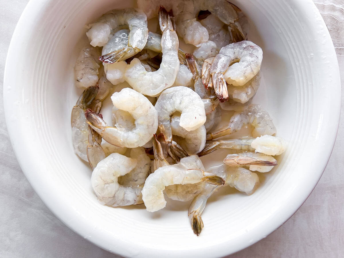 Raw shrimp in a white bowl.