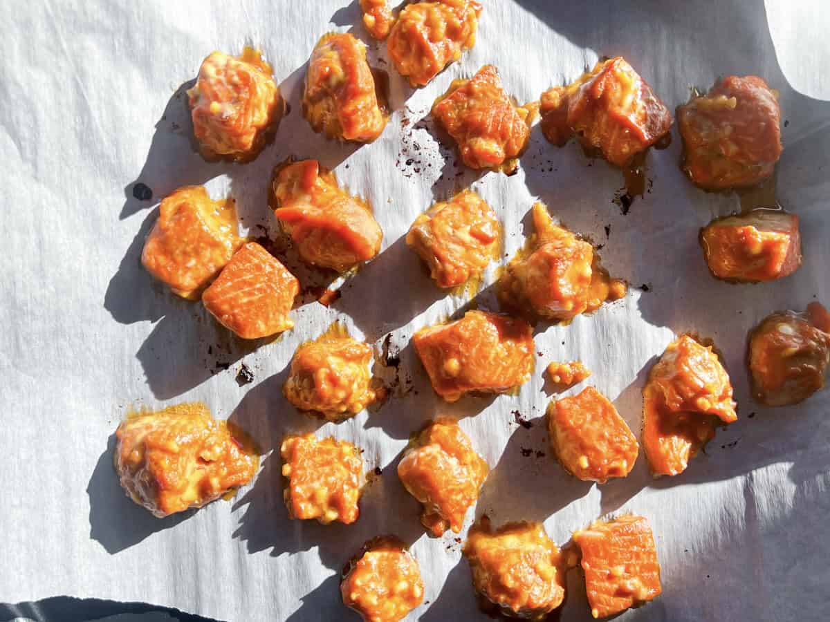 Cooked salmon in cubes on a baking sheet.