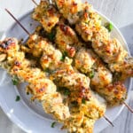 Finished garlic parmesan chicken skewers on a white plate.