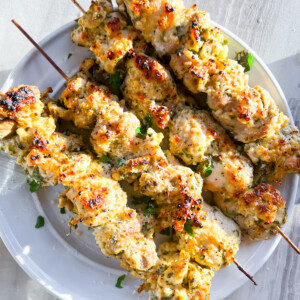 Finished garlic parmesan chicken skewers on a white plate.