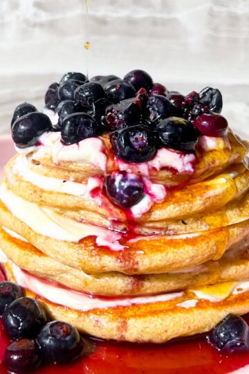 Protein pancakes without protein powder with blueberries on top on a pink plate.