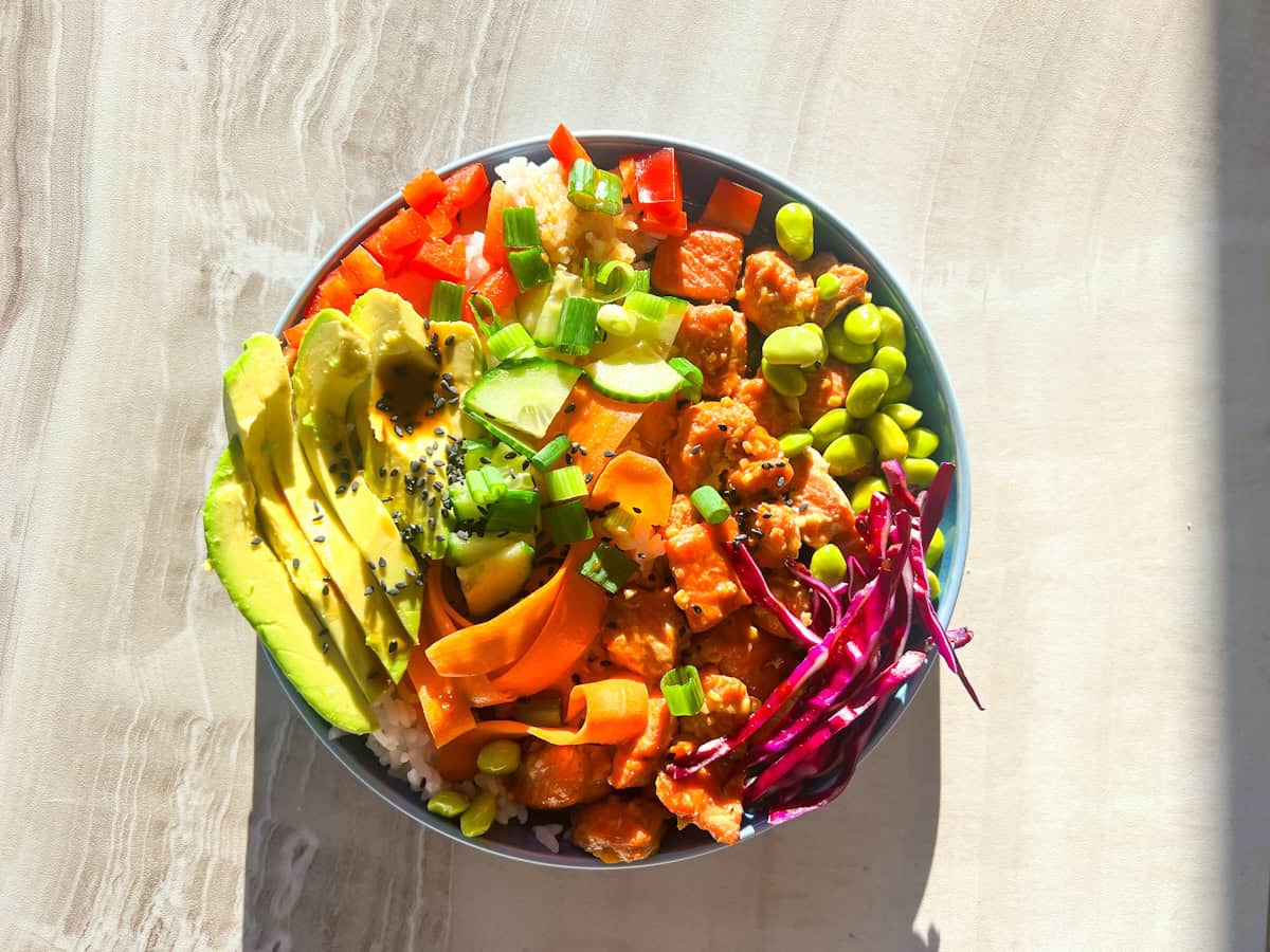 Cooked salmon poke in a blue bowl with all of the toppings.