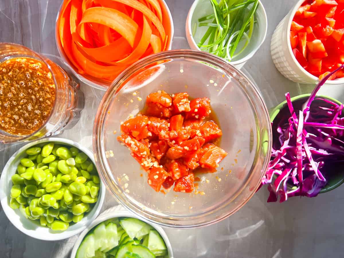 Salmon poke bowl ingredients in clear bowls.