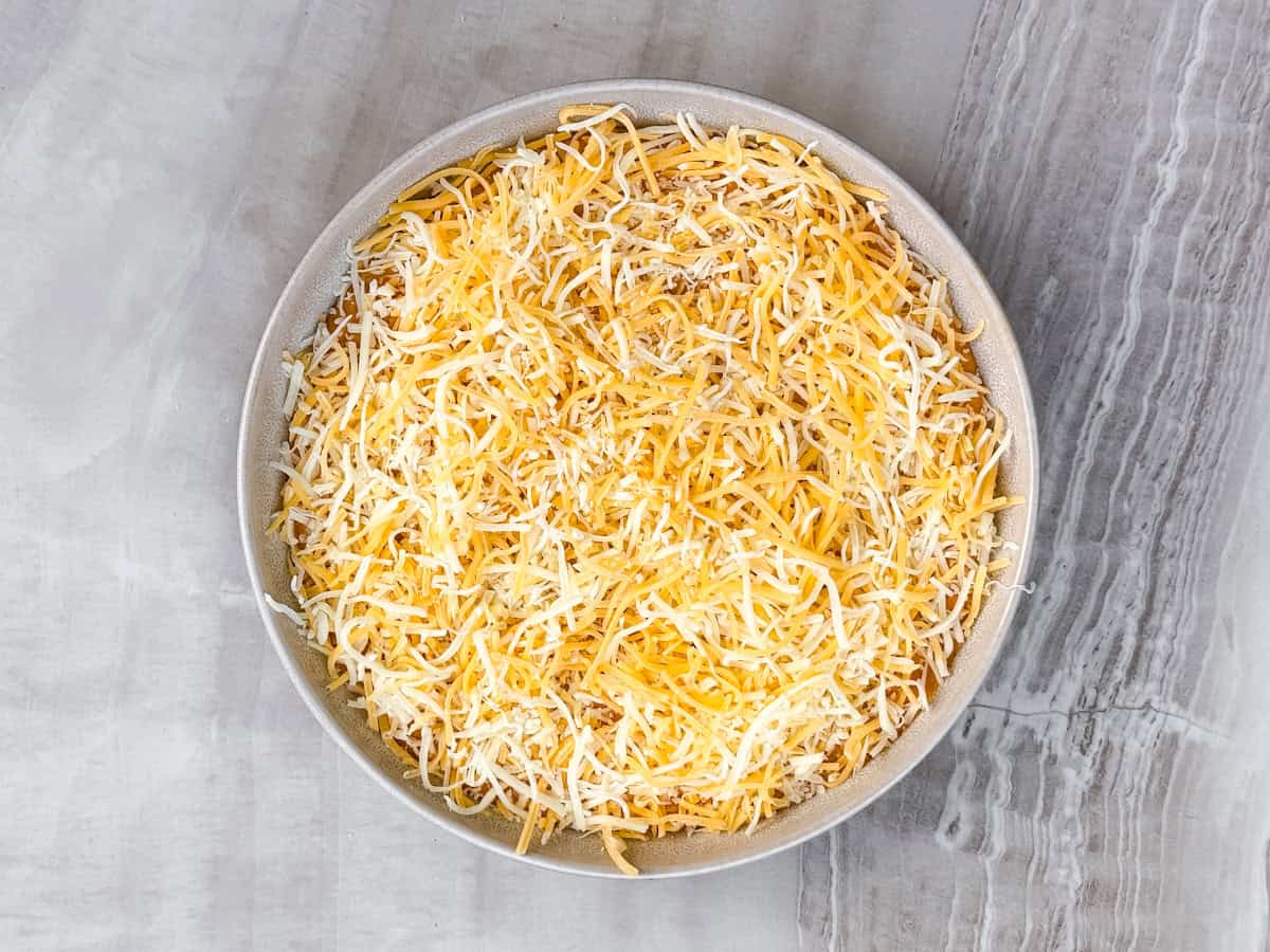 Queso with shredded cheese on top of it.