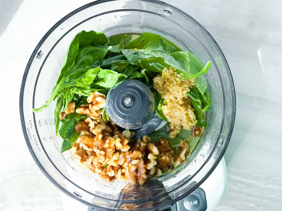 Pesto without pine nuts ingredients in the food proceesor.