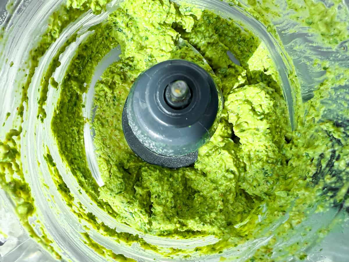 Pesto without pine nuts partially blended in the food processor.