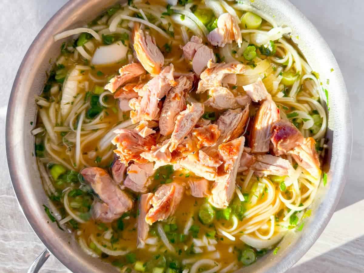 chicken being added to the soup broth.
