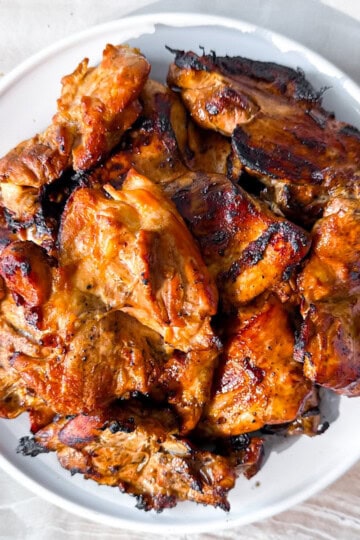 The best grilled boneless chicken thighs on a white plate.