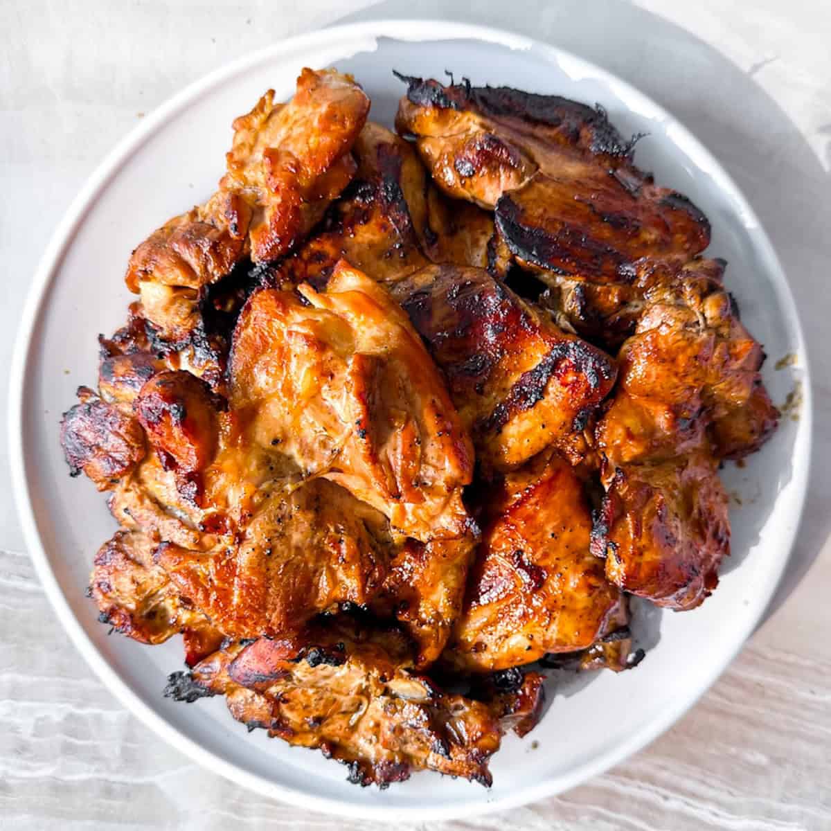 The best grilled boneless chicken thighs on a white plate.