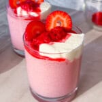 Finished raspberry chia pudding in a cup topped with raspberries and greek yogurt.