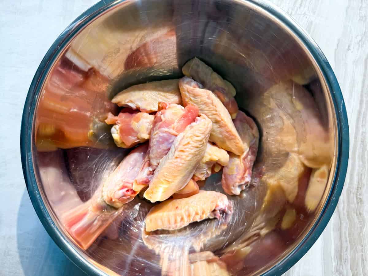 Raw chicken wings in a bowl.