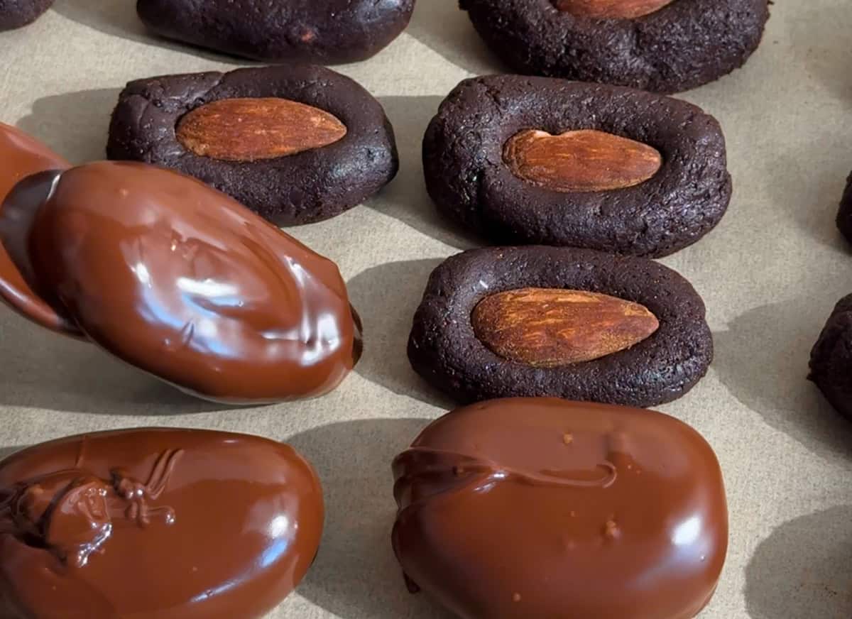 Date candy bites being dipped in chocolate.