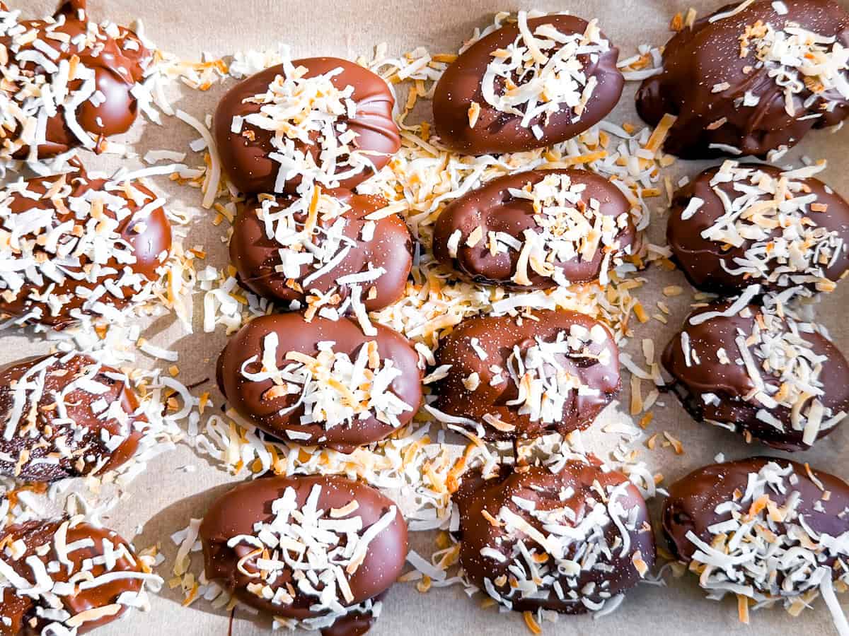 Healthy date candy on parchment topped with shredded coconut.