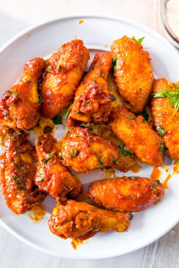 Finished gluten-free chicken wings on a white plate.