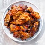 Grilled boneless chicken thighs on a white plate.