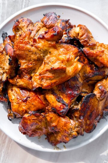 Grilled boneless chicken thighs on a white plate.