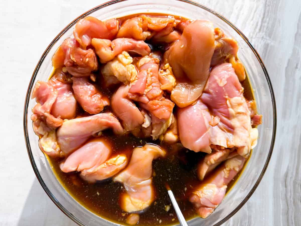 Raw chicken thighs marinating in tamari, lemon juice, garlic powder and salt.