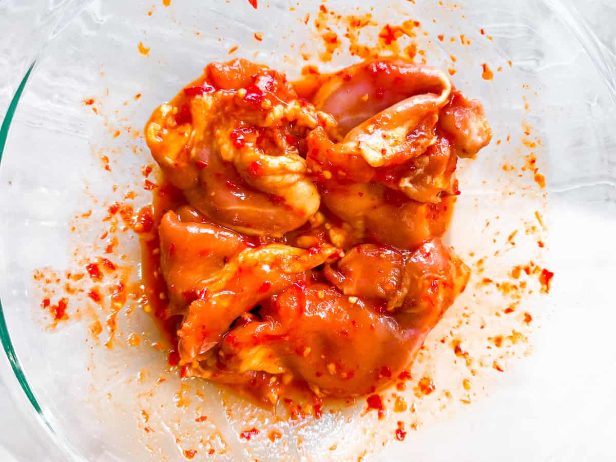 Chicken thighs marinading in harissa marinade.
