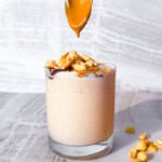 Peanut butter smoothie with a spoon adding peanut butter.