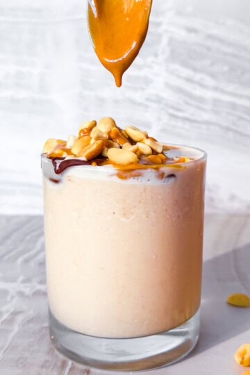 Peanut butter smoothie with a spoon adding peanut butter.