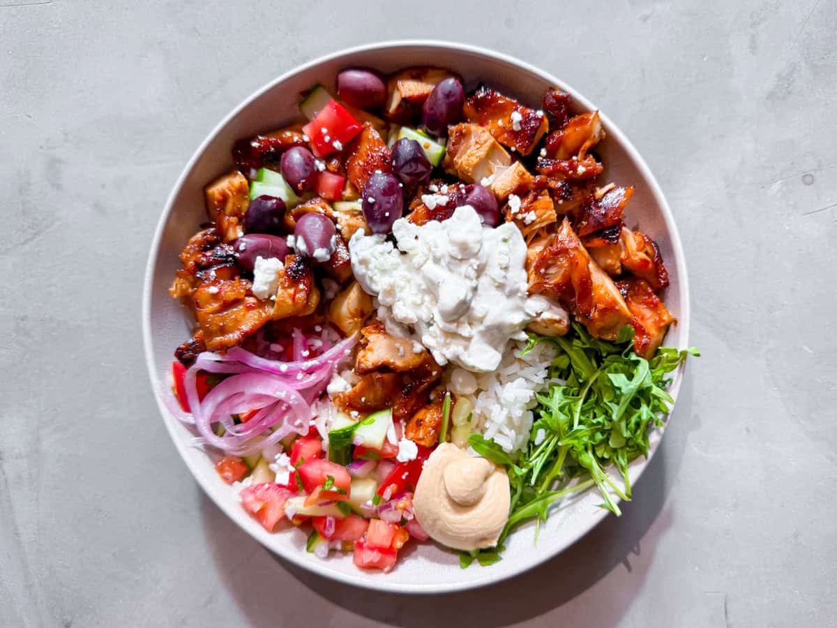 Harissa honey chicken bowls finished on a cement table.