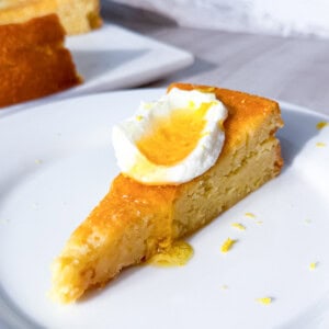 A slice of lemon olive oil cake on a white plate topped with greek yogurt.