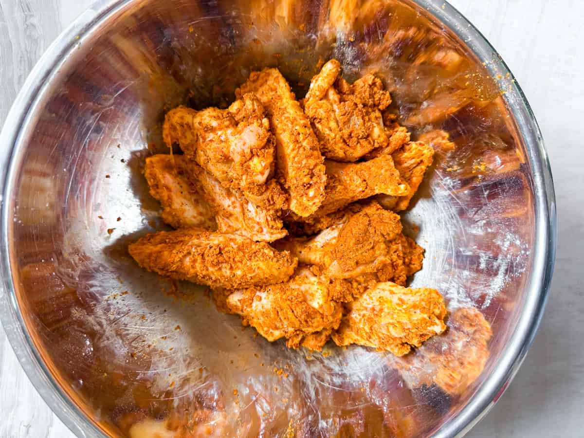 Seasoned raw chicken wings in a bowl.