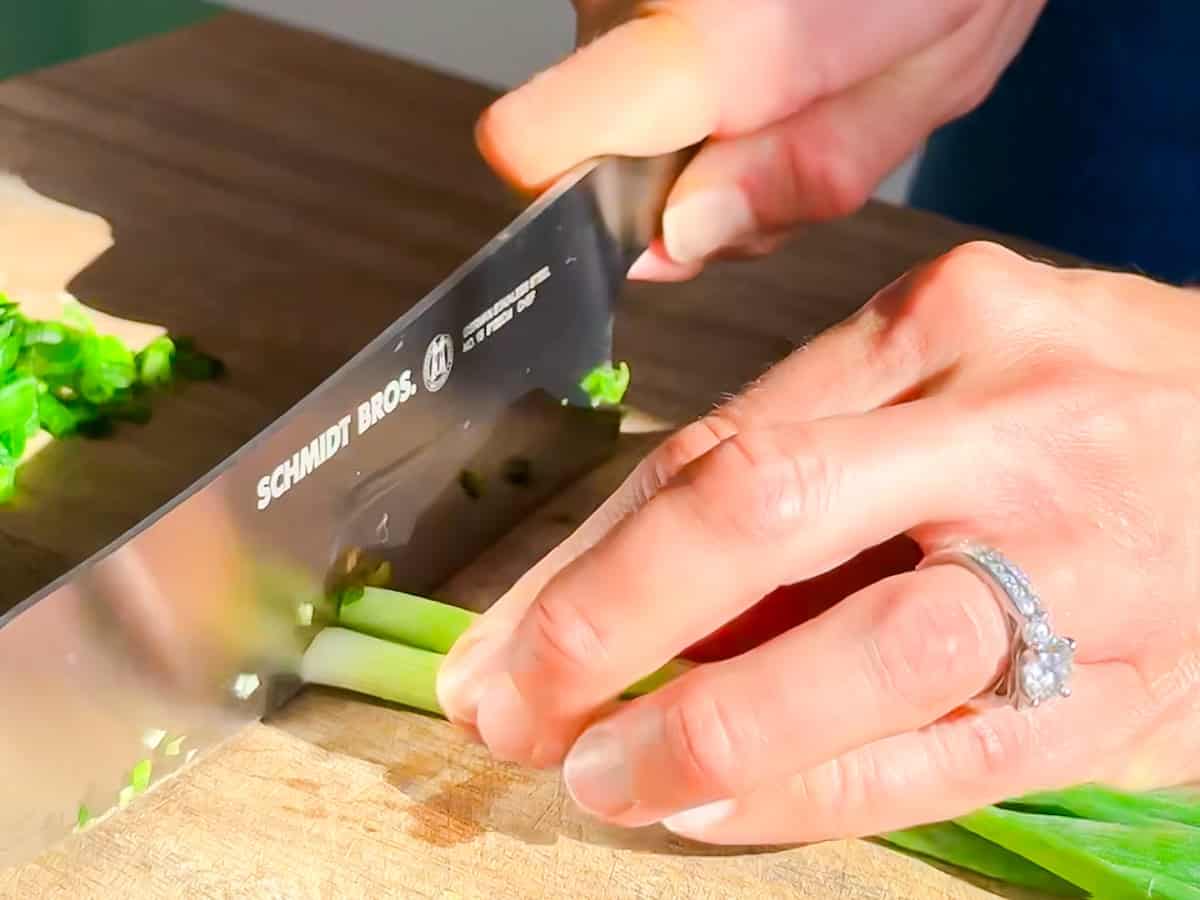 Cutting green onions on a wooden cutting board.
