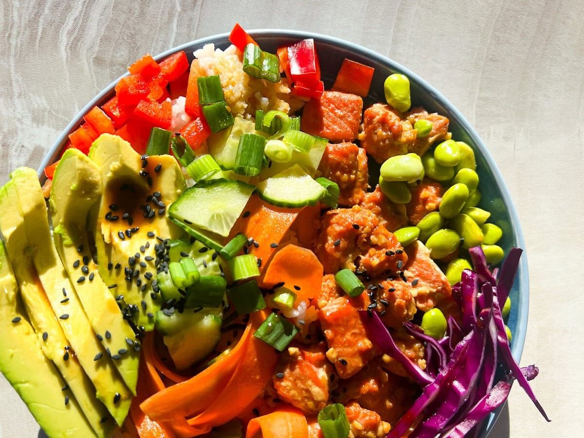Salmon poke bowl in a blue bowl with all of the ingredients.