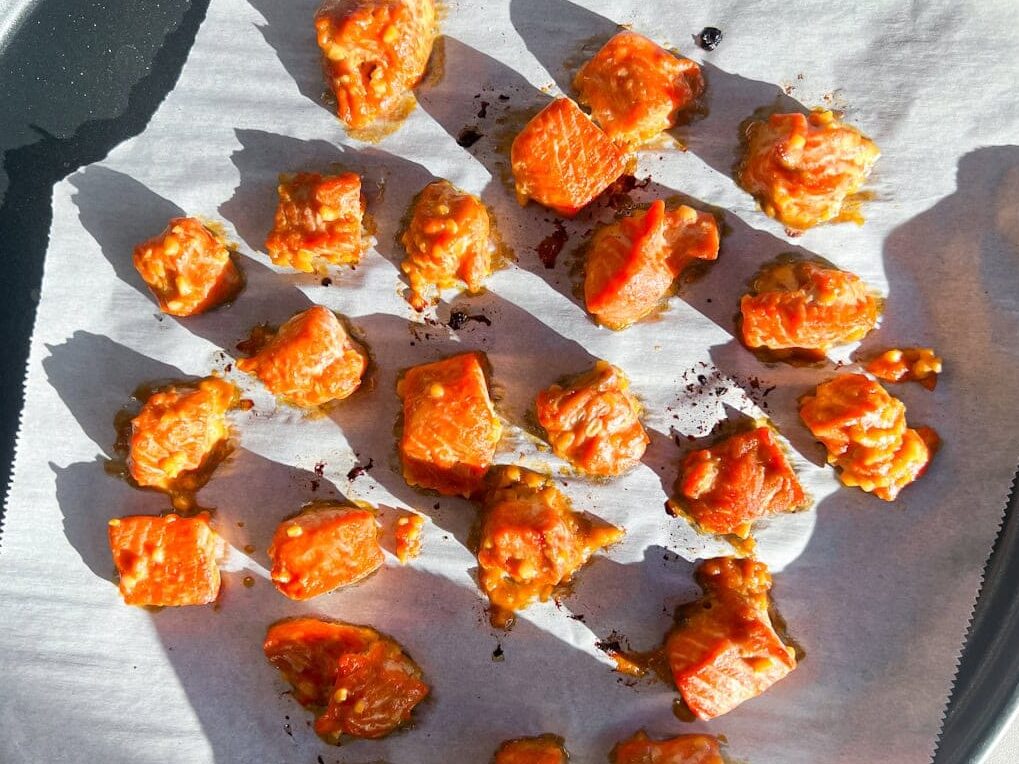 Cooked salmon in cubes on a baking sheet.