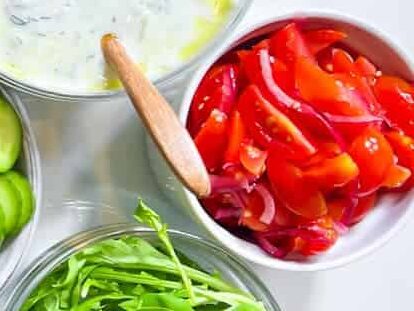 Tomato and onion salad in a white bowl.