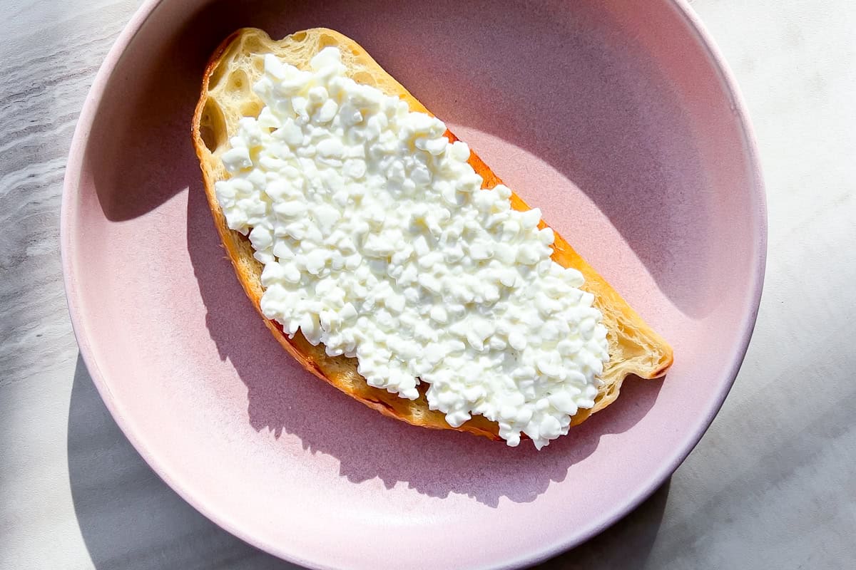A piece of toast with cottage cheese spread on it.