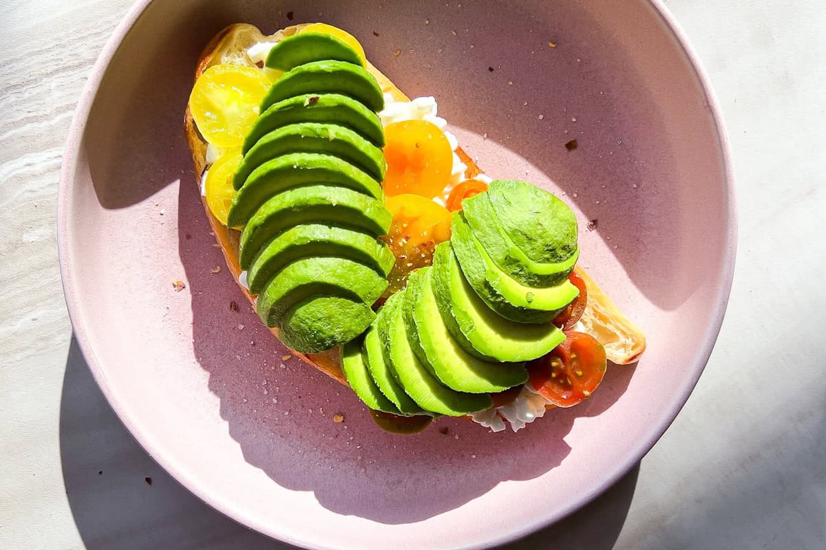 Avocado toast on a pink plate.