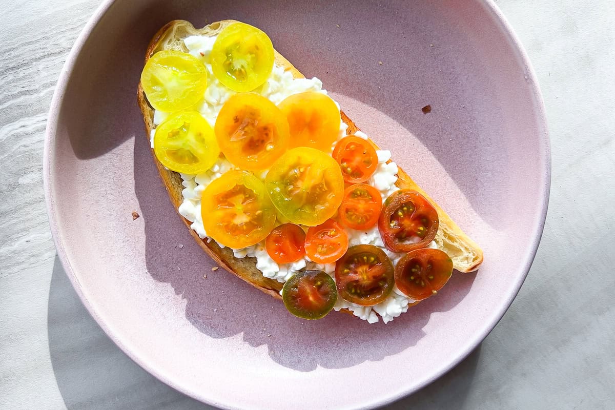 A piece of toast with cottage cheese and tomatoes on it.