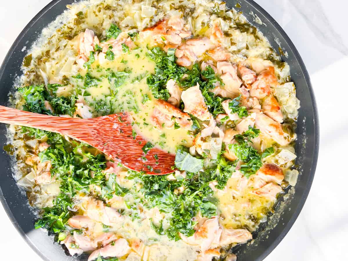 Chicken and kale being added to the chicken piccata soup.