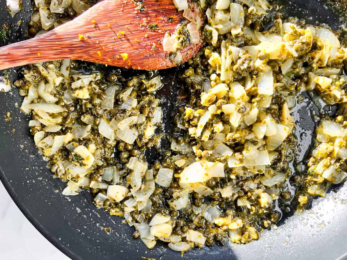 Sautéed veggies and capers in a pan.