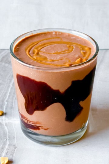Finished chocolate peanut butter smoothie in a cup topped with peanut butter.