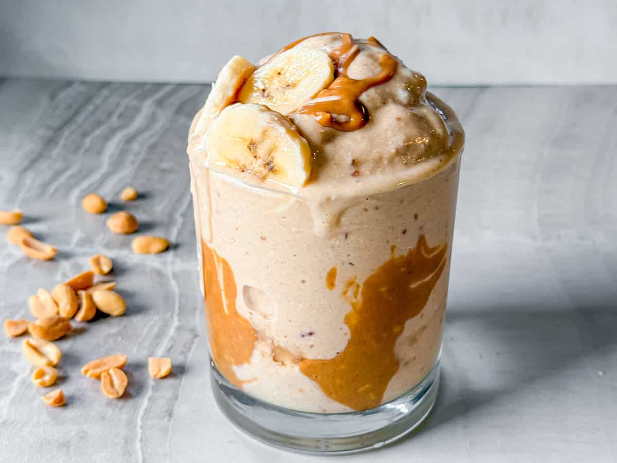 Peanut butter banana smoothie topped with peanut butter and banana slices.