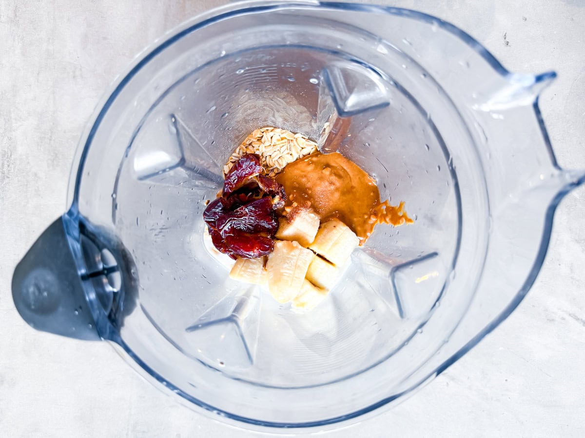 Dates, peanut butter, frozen banana, almond milk, and ice in a blender.