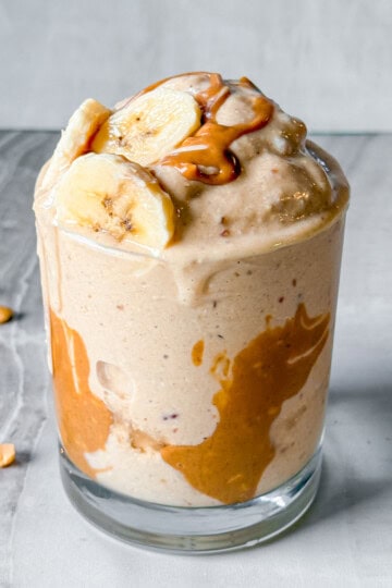 Peanut butter banana smoothie topped with peanut butter and banana slices.