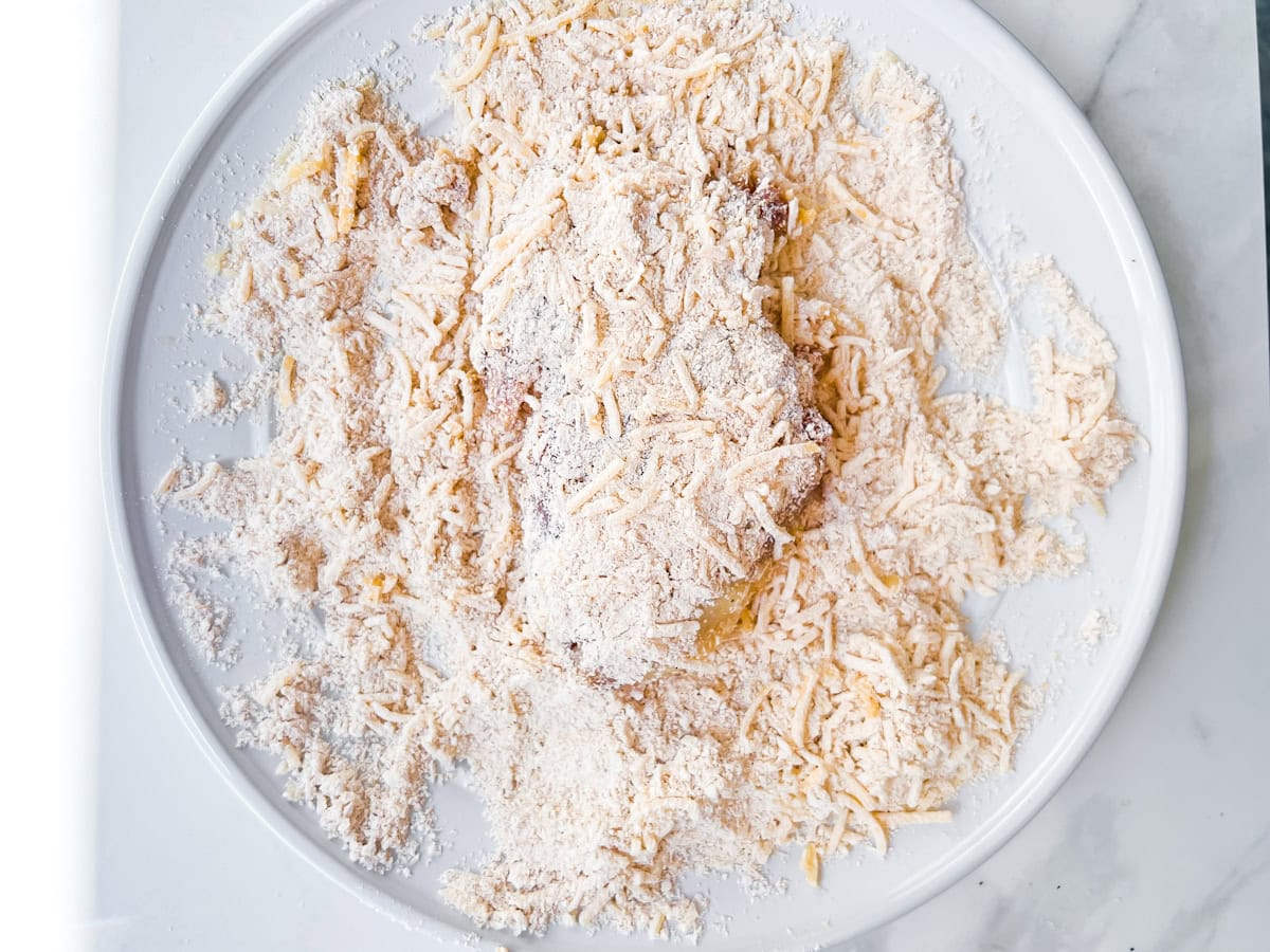 Chicken thigh covered in oat flour parmesan cheese mixture.