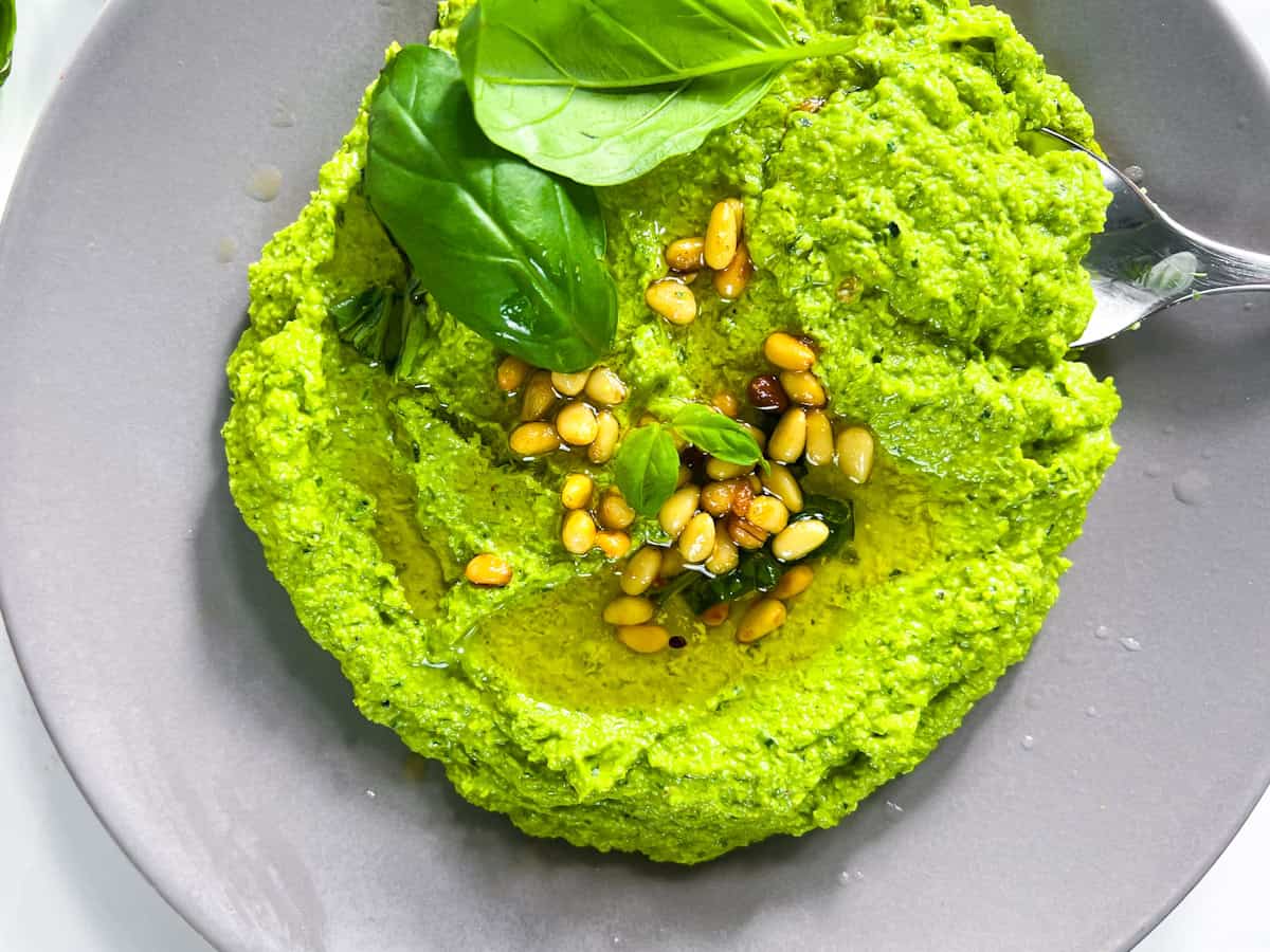 Wild ramp pesto on a gray plate topped with pine nuts.
